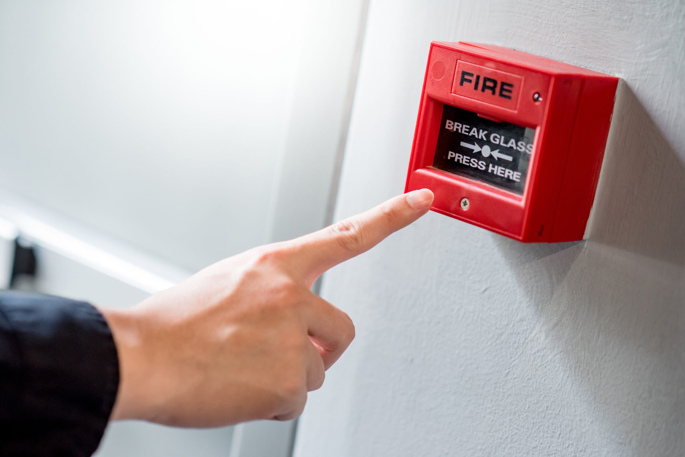 Male,Hand,Pointing,At,Red,Fire,Alarm,Switch,On,Concrete